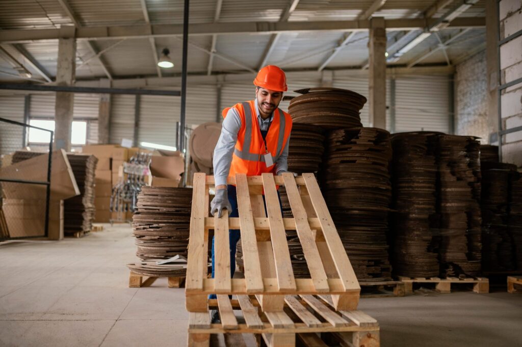 Homem carregando um pallet de madeira.